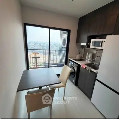 Modern kitchen with balcony view, featuring sleek appliances and dining area.