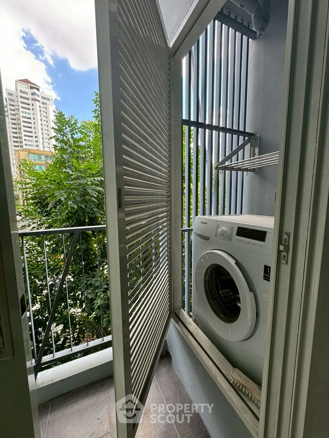Compact balcony with washing machine and city view, ideal for urban living convenience.