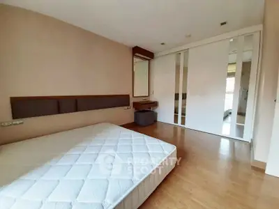 Spacious bedroom with wooden flooring and large sliding closet doors