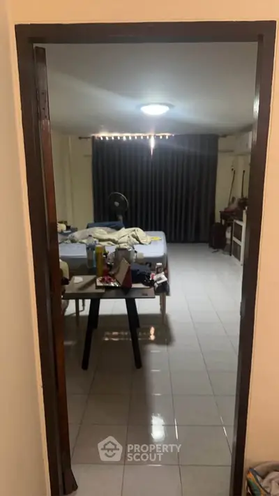 Spacious bedroom with tiled flooring and large window, offering potential for customization.
