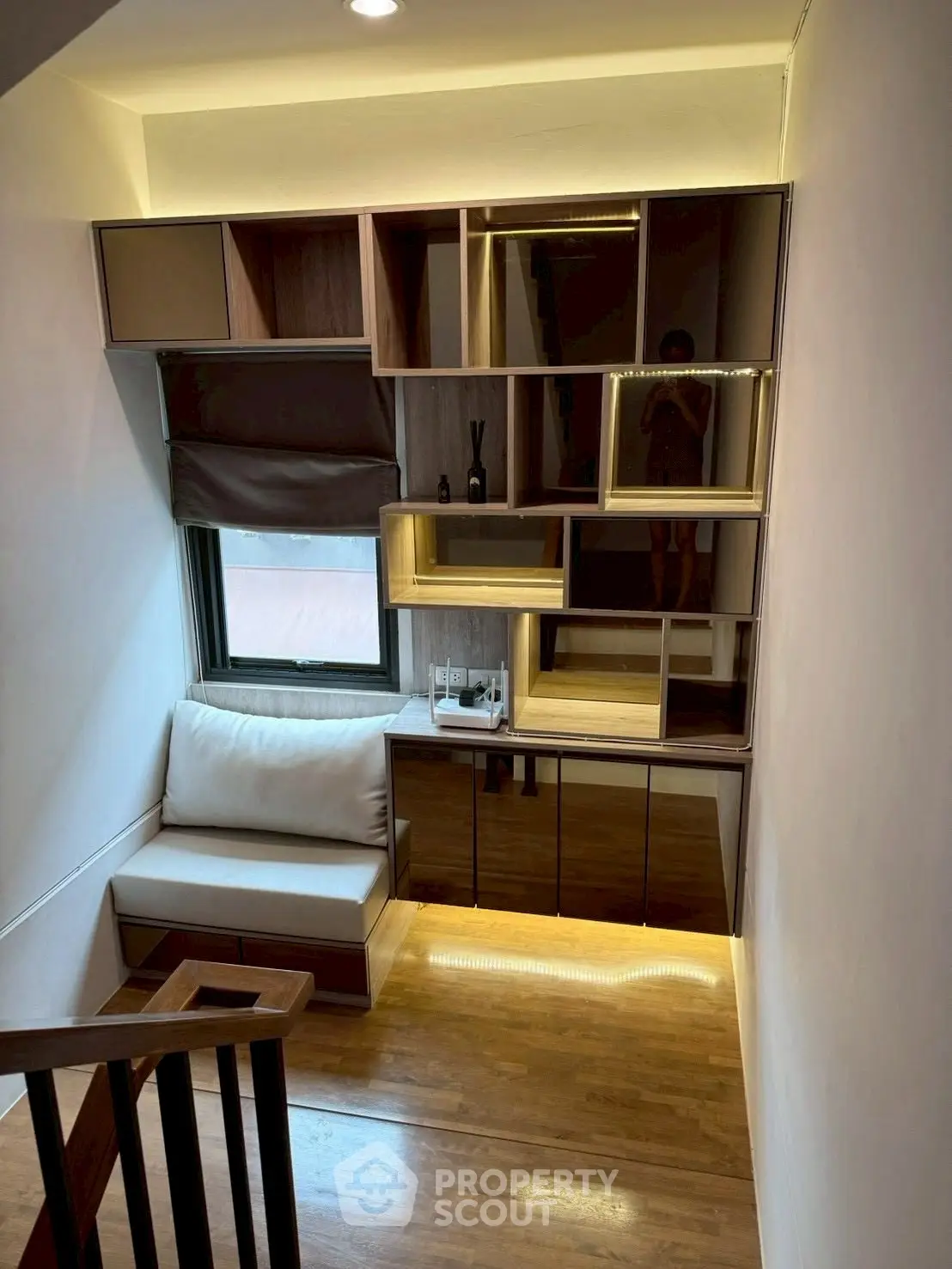 Modern small living area with built-in shelving and cozy seating by window.