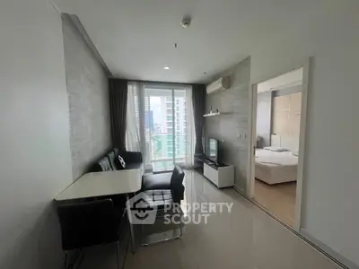 Modern apartment interior with open living and dining area, featuring sleek furniture and a view of the city skyline.