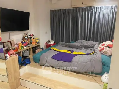 Cozy bedroom with modern decor and entertainment setup, featuring a large TV and ample storage space.