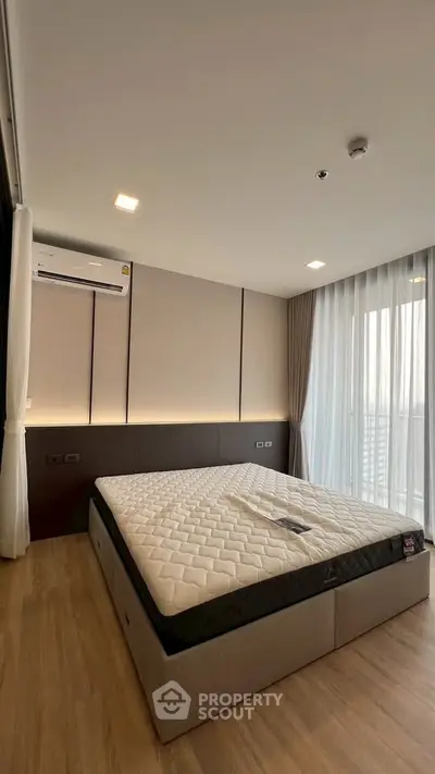 Modern bedroom with large window and stylish decor in a high-rise apartment.