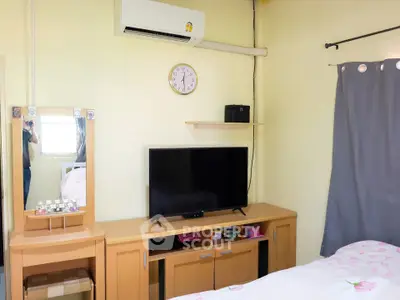 Cozy bedroom with TV and air conditioning, featuring a stylish vanity and modern decor.