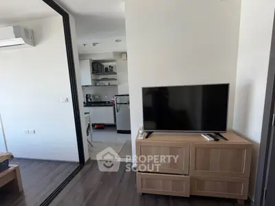 Modern apartment interior with sleek kitchen and cozy living area featuring a flat-screen TV.