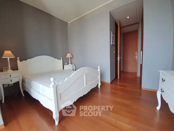 Spacious bedroom with elegant white furniture and wooden flooring