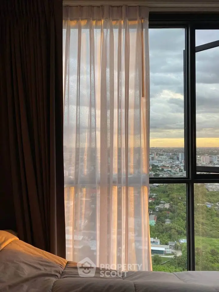 Stunning city view from a cozy bedroom window with soft curtains and warm lighting.