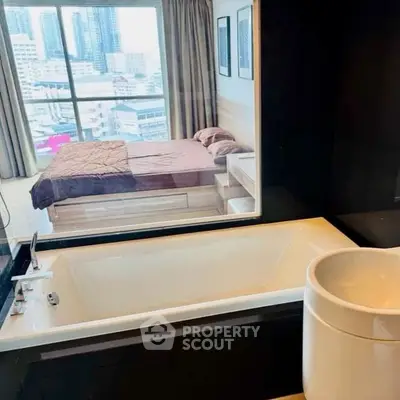 Modern bathroom with bathtub and city view through bedroom window.