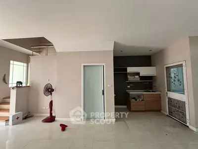 Spacious open-plan living area with modern kitchen and staircase, ideal for contemporary living.