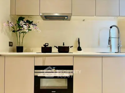 Modern kitchen with sleek cabinetry and built-in oven, featuring a stylish faucet and decorative plant.