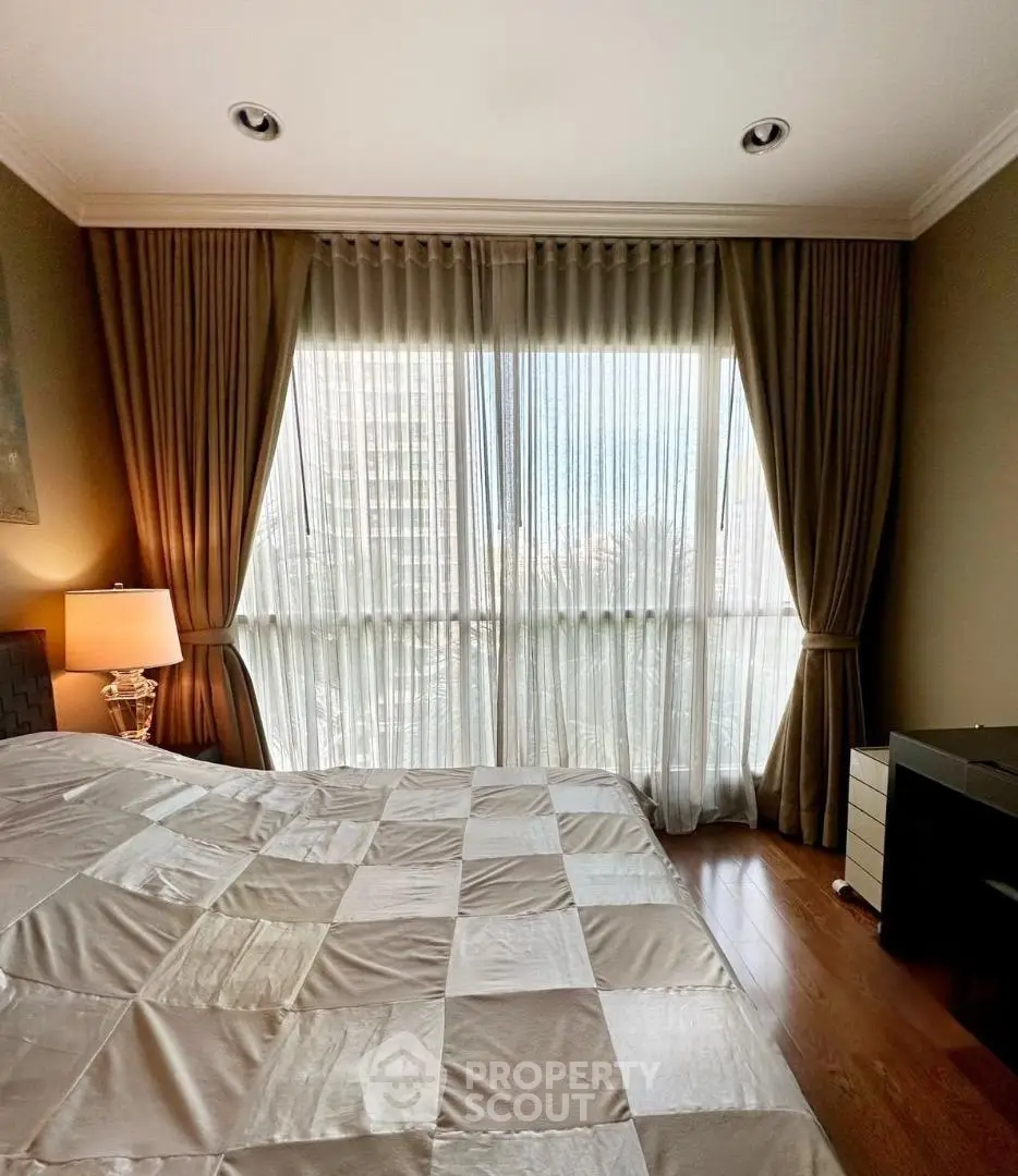 Elegant bedroom with large window and luxurious curtains, featuring a cozy bed and stylish lamp.