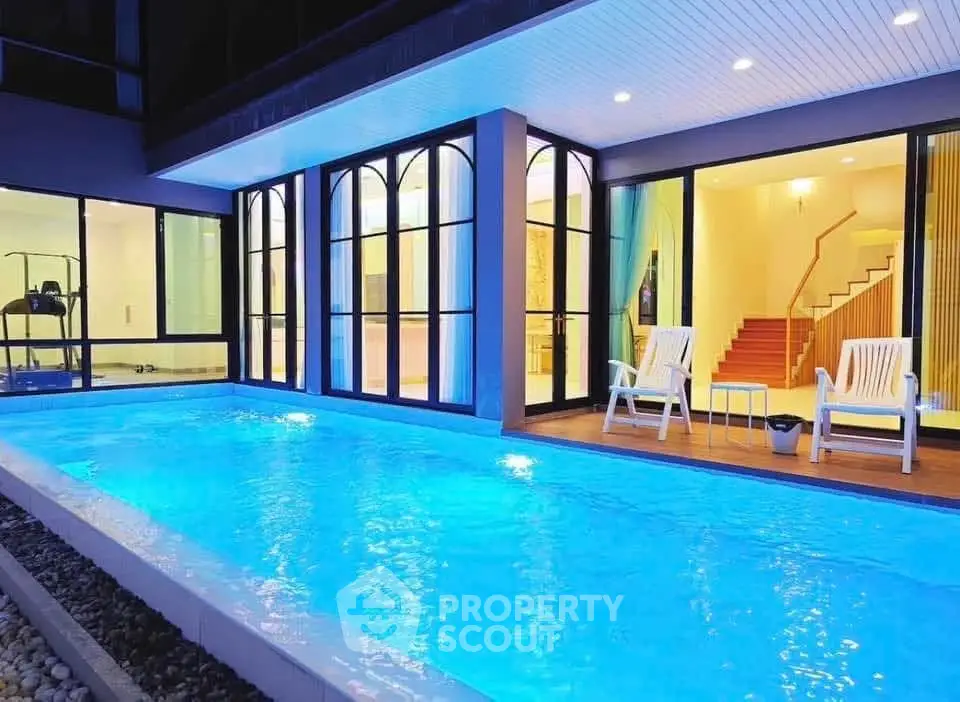 Luxurious modern home with illuminated pool and elegant glass facade, perfect for evening relaxation.