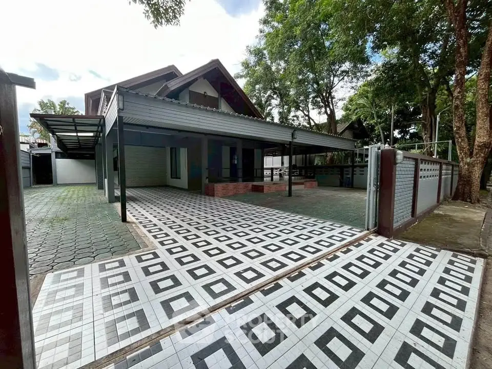 Charming suburban home with spacious driveway and modern tiled entrance, surrounded by lush greenery.