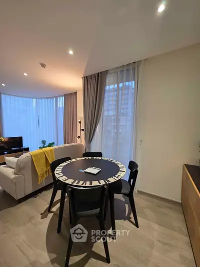 Modern living room with stylish dining area and large windows in a contemporary apartment.