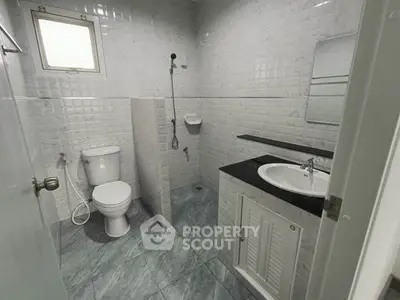 Modern bathroom with sleek fixtures and tiled walls, featuring a shower and vanity.