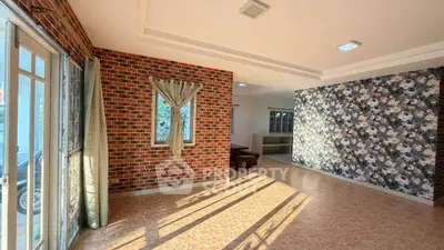 Spacious living room with brick accent wall and floral wallpaper, featuring large windows for natural light.
