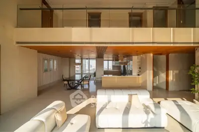 Luxurious modern living room with open kitchen and elegant furnishings, featuring floor-to-ceiling windows and mezzanine.