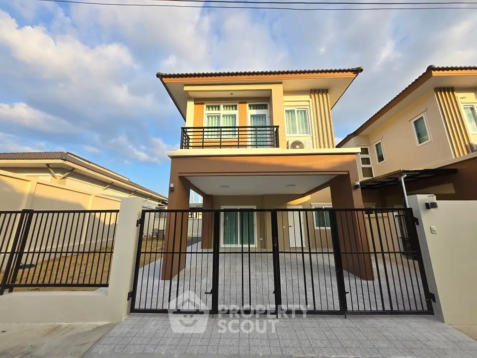 Modern two-story house with gated driveway and contemporary design.