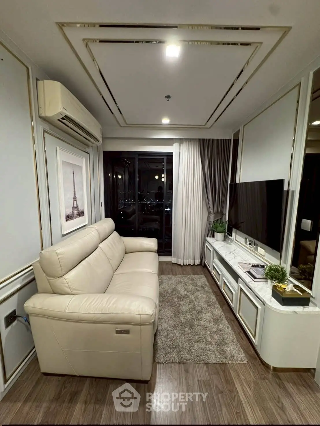 Luxurious living room with elegant decor and city view, featuring a plush sofa and modern entertainment setup.