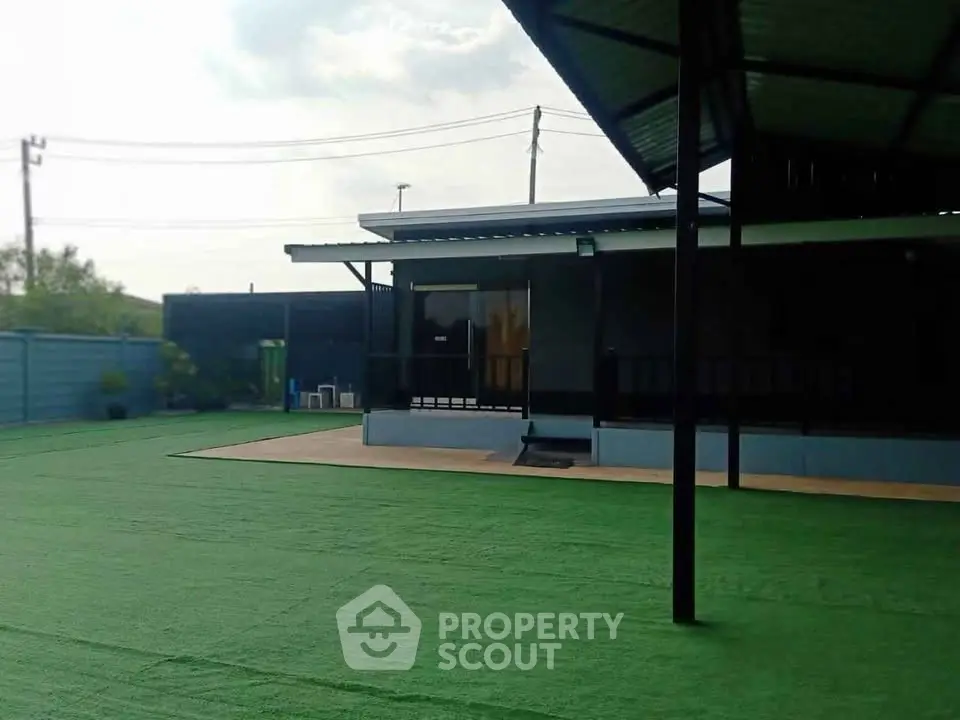 Spacious outdoor area with artificial grass and modern building exterior, perfect for gatherings.