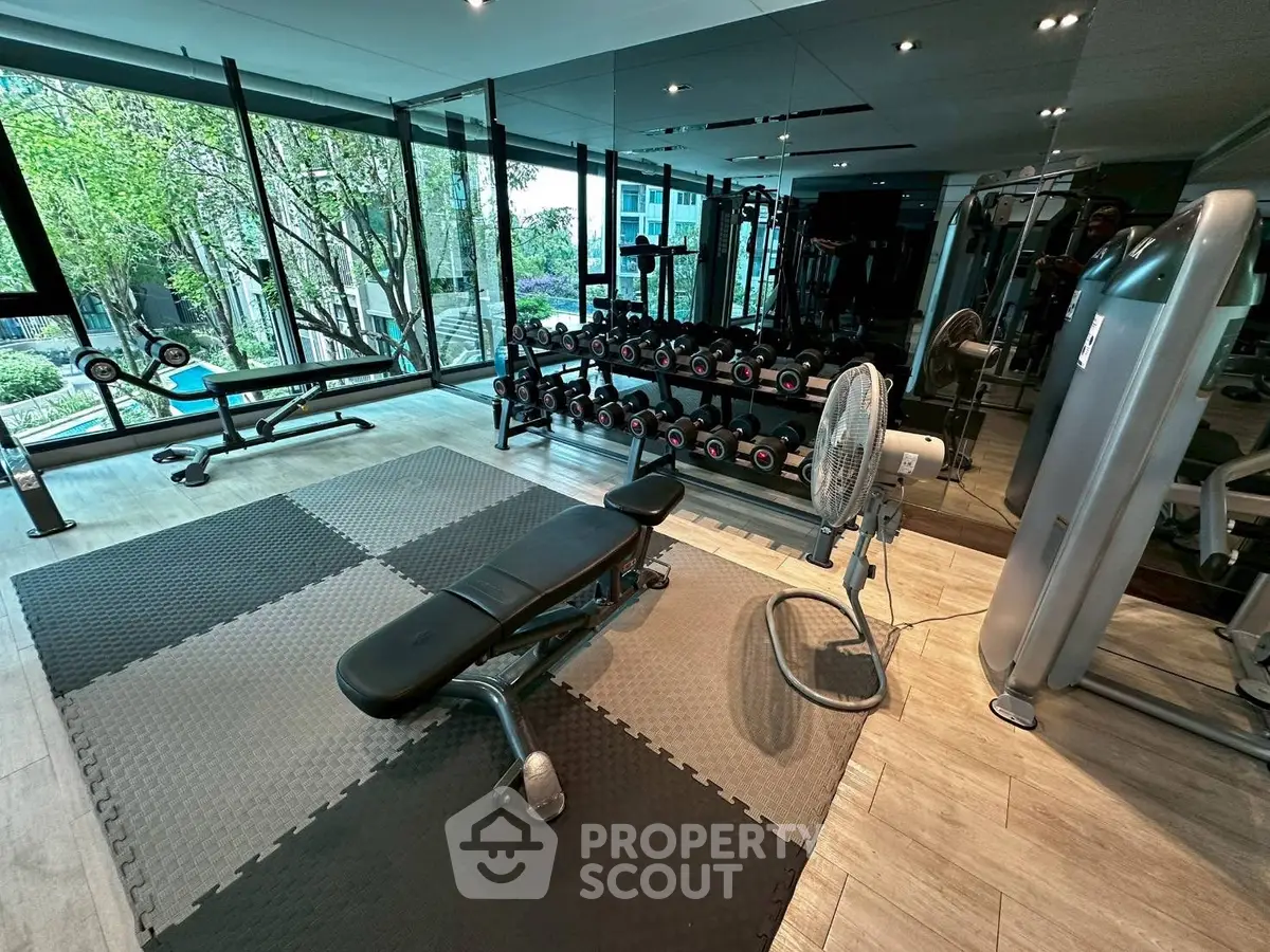 Modern gym with large windows and fitness equipment in luxury apartment complex