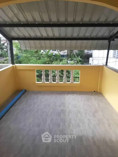Spacious covered balcony with tiled flooring and garden view, perfect for relaxation.