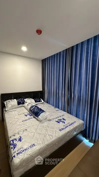 Modern bedroom with stylish blue curtains and cozy bed setup in a contemporary apartment.