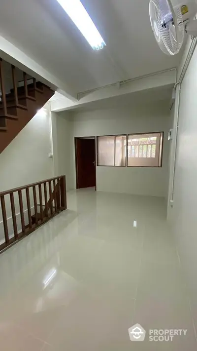 Spacious hallway with glossy tiled floor and wooden staircase in modern home