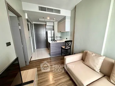 Modern living room with open kitchen and cozy seating area in a stylish apartment.