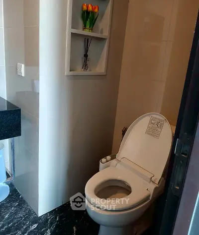 Modern bathroom with sleek toilet and elegant black marble flooring.