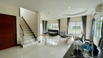 Spacious modern living room with elegant staircase and large windows for natural light.