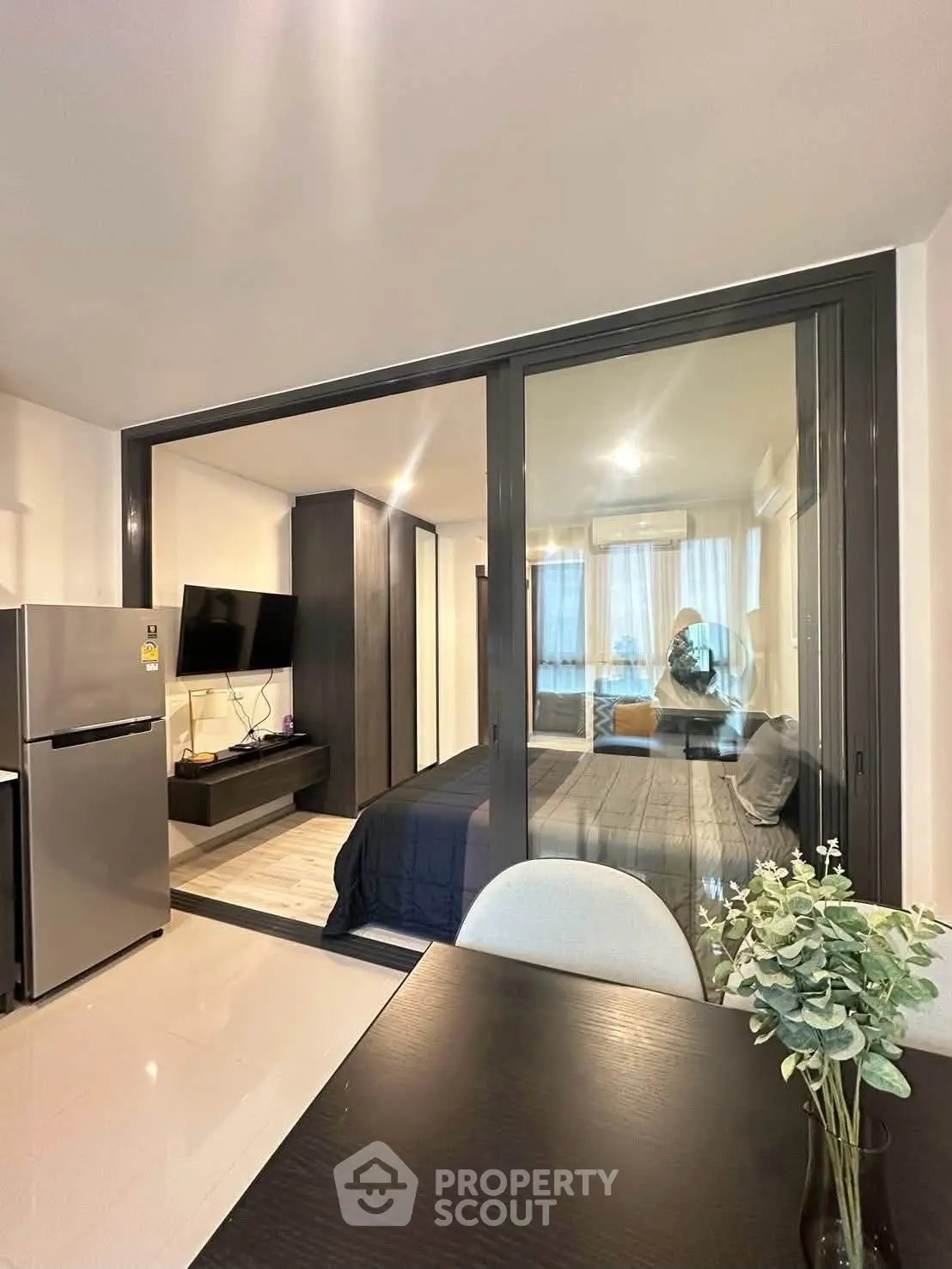 Modern apartment interior with open layout, featuring a sleek kitchen and cozy living area with glass partition.
