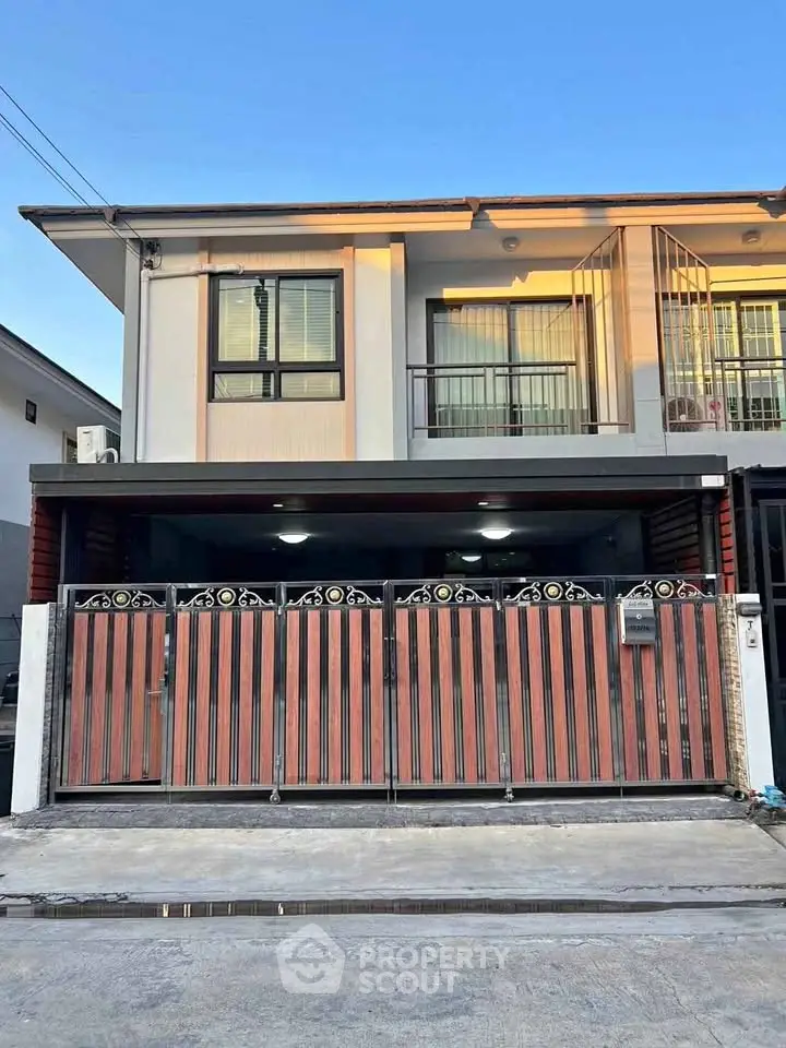 Modern two-story house with stylish wooden gate and balcony, perfect for family living.