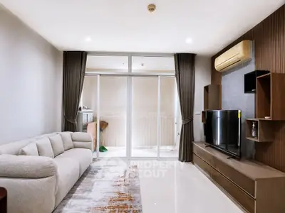 Modern living room with sleek furniture and large glass doors leading to a balcony, perfect for relaxation.