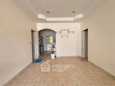 Spacious empty room with tiled floor and arched doorway, ideal for customization.