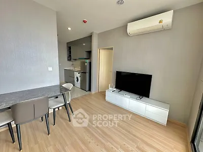 Modern living room with dining area and kitchen featuring sleek furniture and appliances.