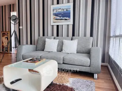 Stylish modern living room with gray sofa, striped wallpaper, and chic decor accents.