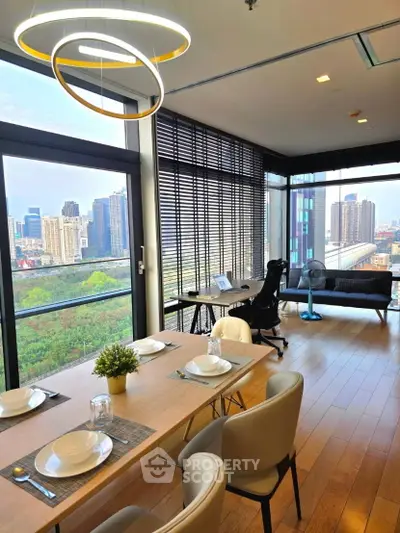 Modern living room with city view, stylish dining area, and workspace in a high-rise apartment.