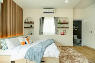 Cozy bedroom with modern decor and ensuite bathroom, featuring stylish shelving and plush bedding.
