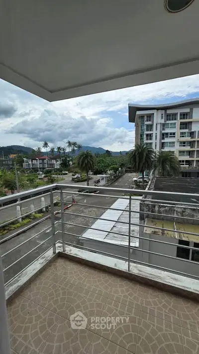 Spacious balcony with scenic view of modern residential complex and lush greenery.