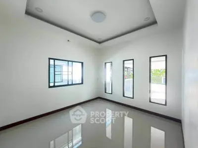 Spacious empty room with large windows and glossy tiled floor in modern home.