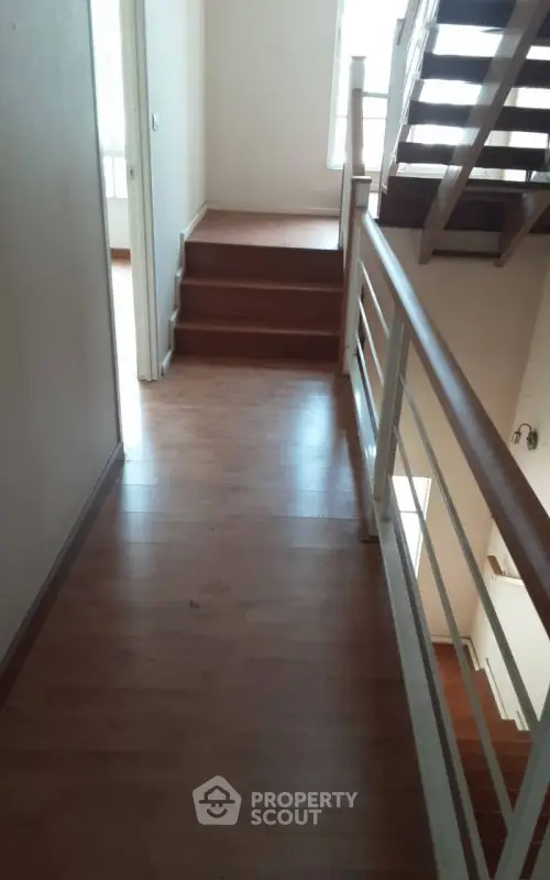 Spacious hallway with wooden flooring and modern railing in a multi-level home.