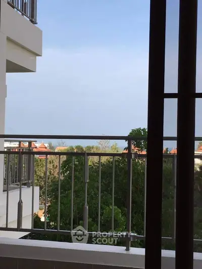 Stunning balcony view with lush greenery and distant rooftops, perfect for serene living.
