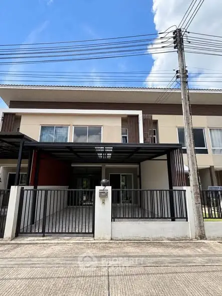 Modern townhouse exterior with gated driveway and sleek design under a clear blue sky.