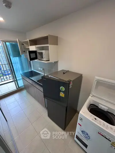 Modern kitchen with appliances and balcony view in urban apartment