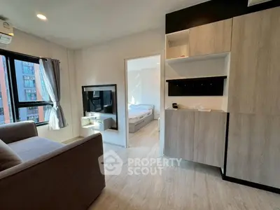 Modern apartment interior with cozy living room and view into a bright bedroom, featuring stylish cabinetry.