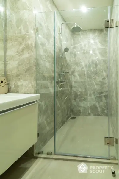 Luxurious modern bathroom with glass shower enclosure and marble walls