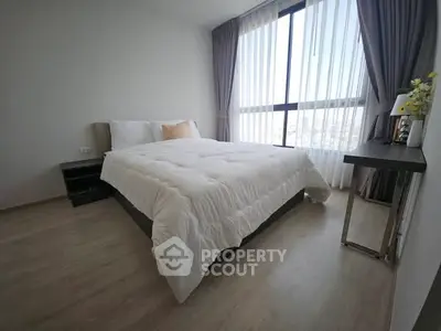Modern bedroom with large window and cozy bedding, offering a bright and inviting atmosphere.