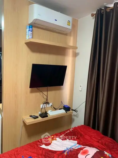 Cozy bedroom with wall-mounted TV and air conditioning, featuring modern decor and a vibrant bedspread.